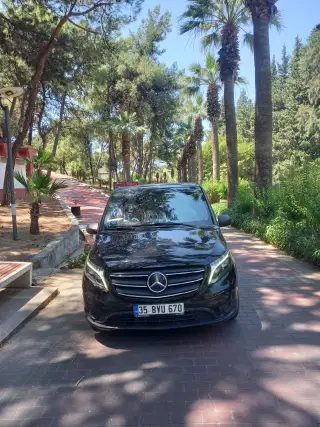 Ağaçlı bir yolda siyah Mercedes Vito transfer aracı, önden görünüm