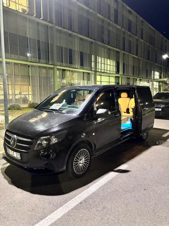 Gece bina girişinde kapısı açık siyah Mercedes transfer aracı
