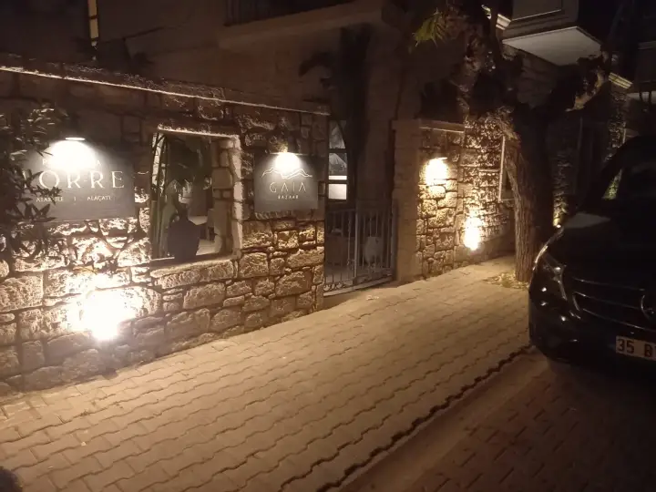 Gece aydınlatılan taş duvarlı girişin yanında siyah transfer aracı