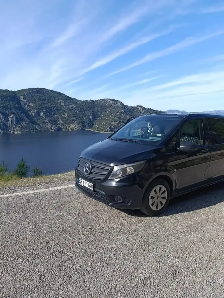 Deniz ve kıyı manzarasının yanında park edilmiş siyah Mercedes Vito
